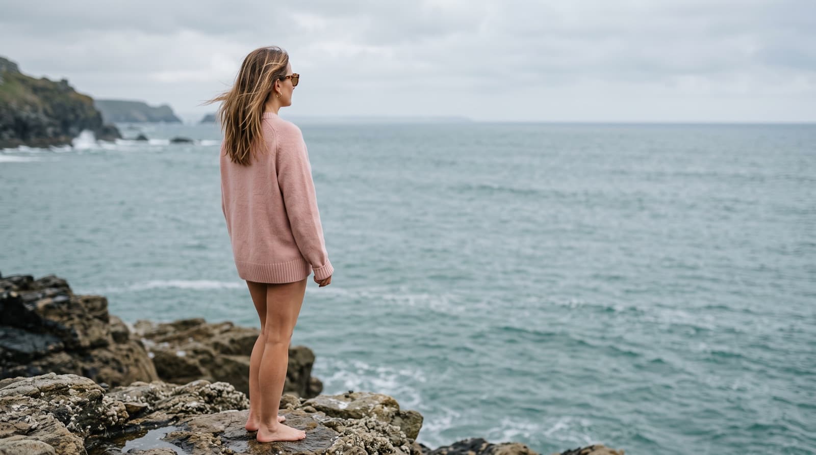 A woman looking out toward the ocean on an overcast day